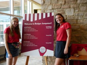 Student staff from the Center for the First-Year Experience welcome #FutureBadgers and their guests in front of a sign.