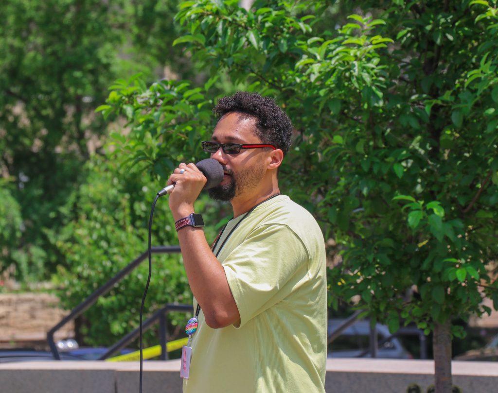 Assistant Dean and Director of the Gender and Sexuality Campus Center, Warren Scherer (Center), speaks in front of the attendees of the Pride Picnic.
