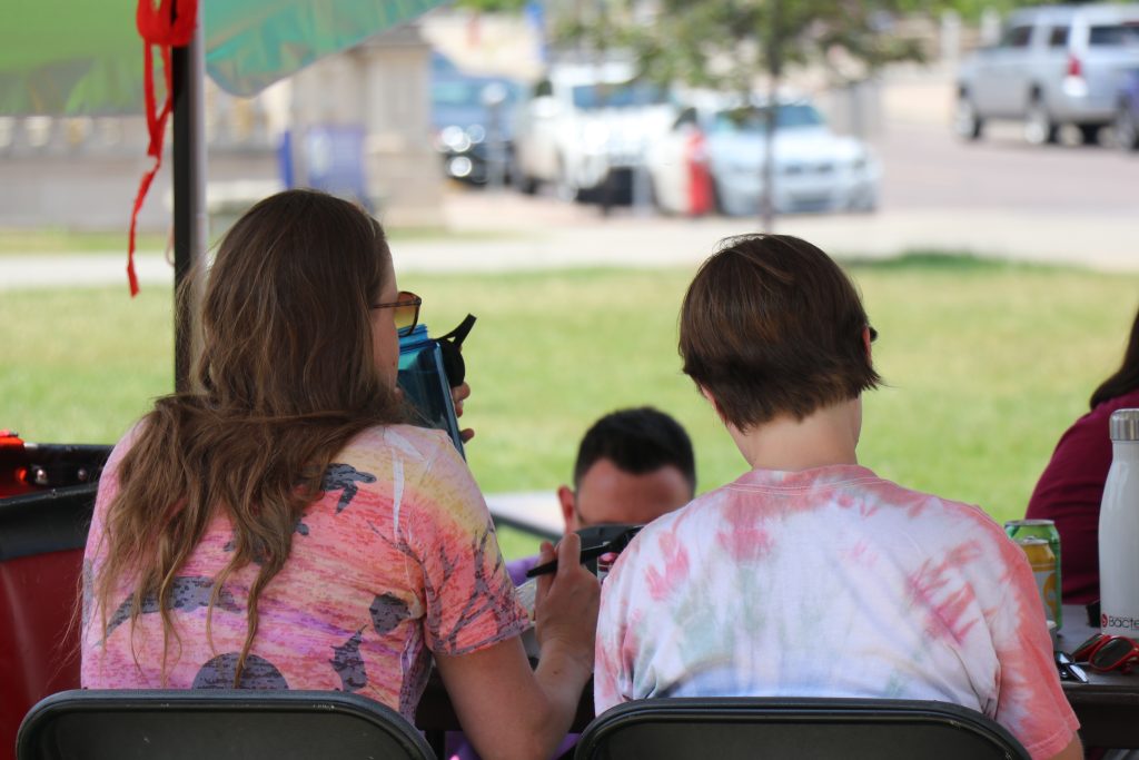 Attendees at the Pride Picnic sitting at the table under a tent and enjoying lunch.