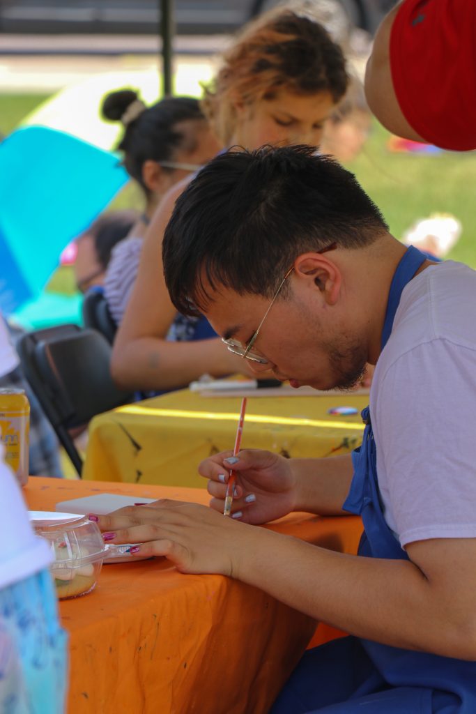 An attendee paints a canvas at the art tent hosted by the Wisconsin Union Wheelhouse Studios at the Pride Picnic.