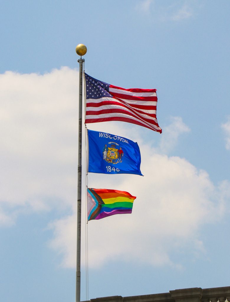 The American Flag, Wisconsin Flag, and Pride Flag flying above the Wisconsin Historical Society Library.