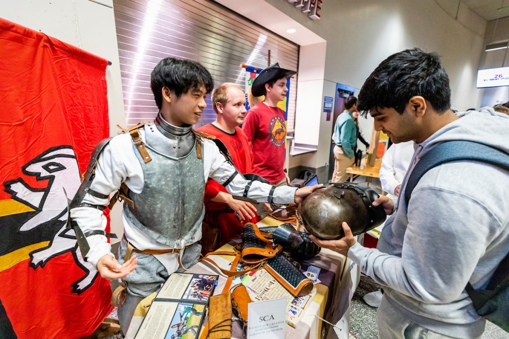 Two students – one from the Society for Creative Anachronism (SCA) – speak at a table at the Student Org Fair.
