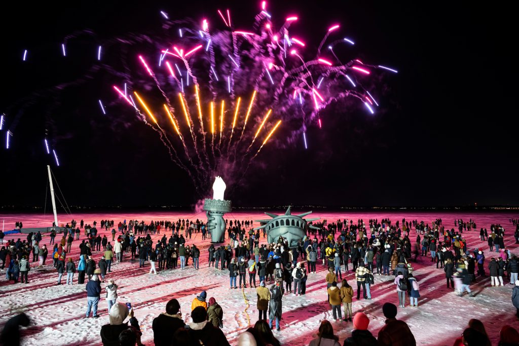 Hundreds of people watch as fireworks launch into the night sky above an inflatable replica of the Statue of Liberty’s head, arm and torch on frozen and ice-covered Lake Mendota.