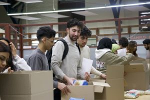 Students seen in a row, preparing care packages at the event.