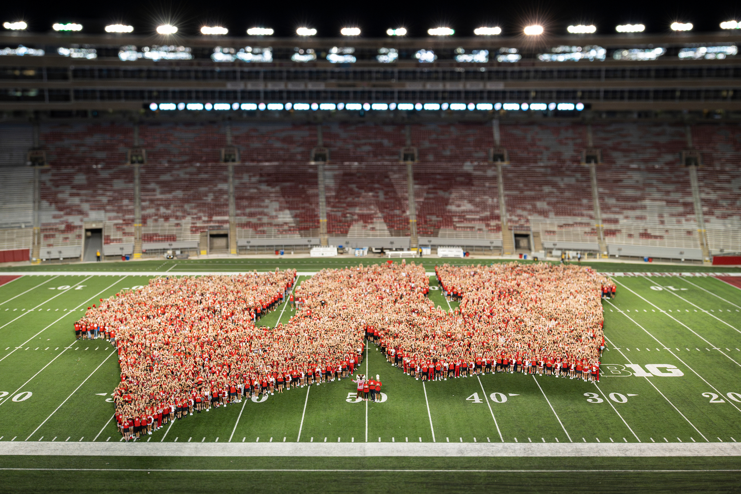 First-year students, along with UW mascot Bucky Badger and Chancellor Mnookin form the shape of an iconic Motion W as part of the W Project on Barry Alvarez Field at Camp Randall Stadium.