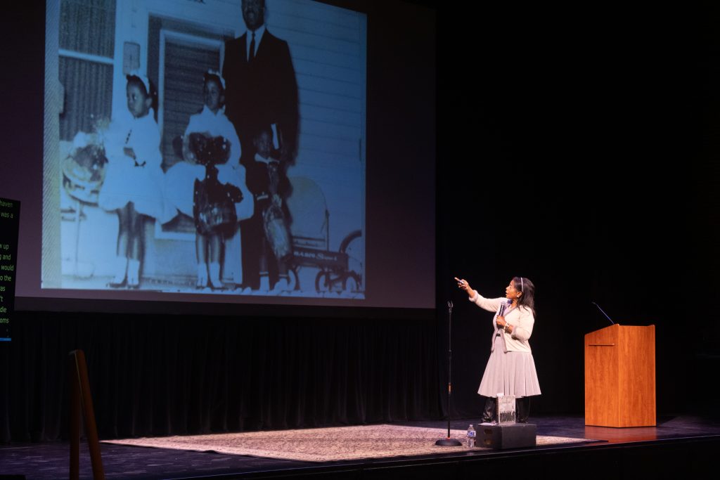 Donzaleigh Abernathy points to the screen on stage. 