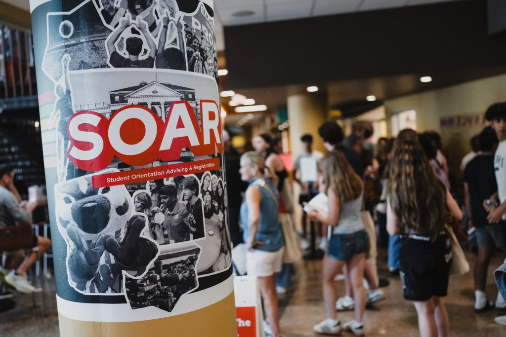 A pillar wrapped with SOAR branding as people walk in the background