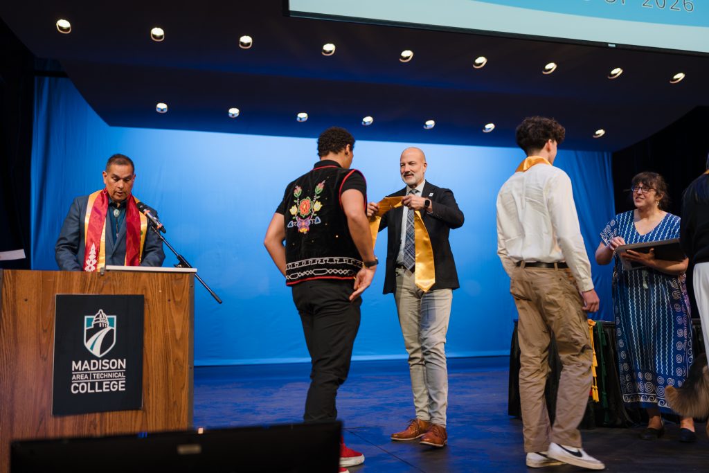 Emcee Aaron Bird Bear and Madison Metropolitan School District superintendent Joe Gothard invites eighth grade students to the stage to receive their stoles and certificates.