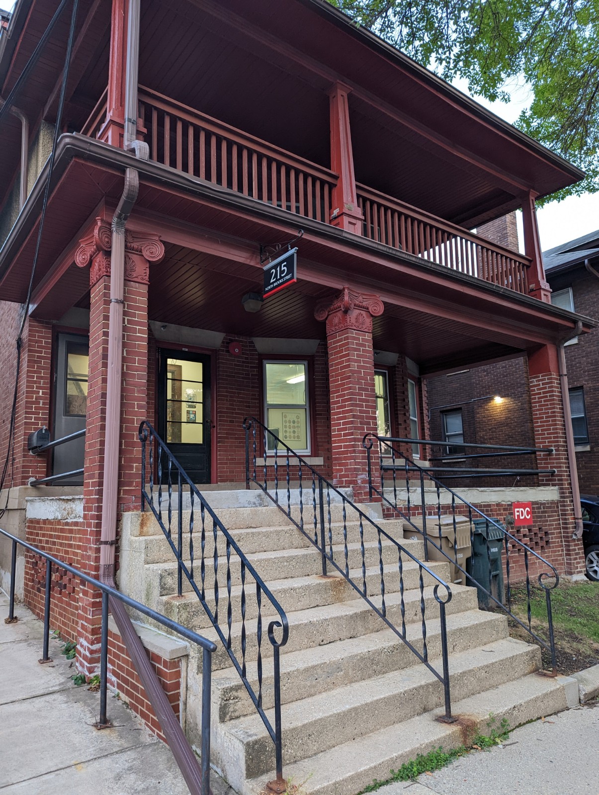 brown brick two story building with porch and stairs