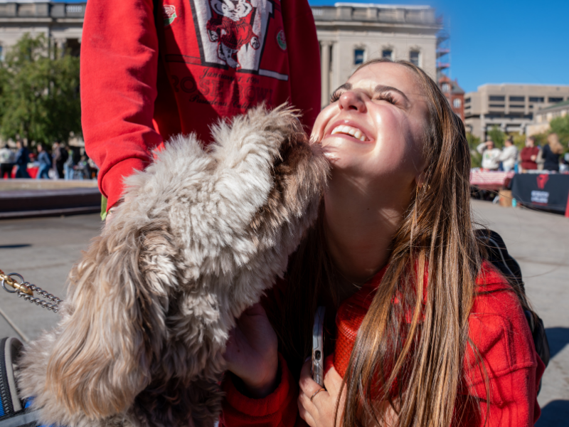 Photo of an individual smiling with a cute white and tan dog