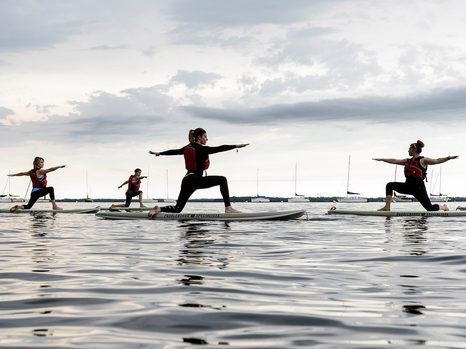 A group of women  balance in yoga poses on paddle boards on Lake Mendota